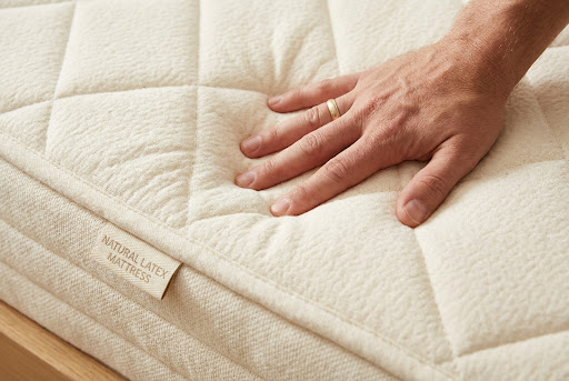 Hand pressing into natural latex showing resilience and comfort